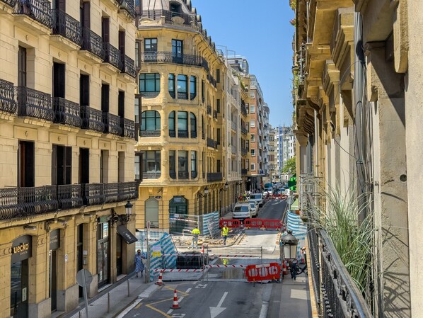 Una calle estrecha flanqueada por edificios, algunos con balcones y otros con comercios en la planta baja.
