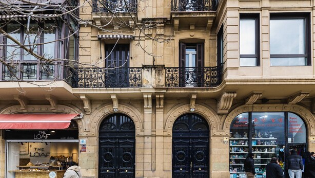 A building with ornate black doors and a bakery named 'The Loaf' on the ground floor.