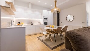 A modern kitchen with white cabinets, a dining table with chairs, and a round mirror on the wall.