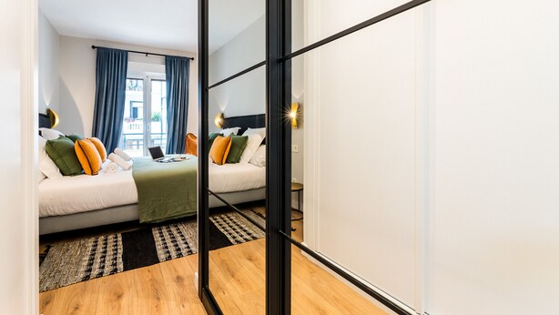 A modern hotel room with a bed, a desk, and a view of the outdoors. - GRAN VIA SUITE: superior apartment for 6 PAX. 2min from the beach (San Sebastián)