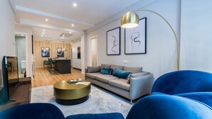 A modern living room with a sofa, blue chairs, a coffee table, and artwork on the wall. - GRAN VIA SUITE: superior apartment for 6 PAX. 2min from the beach (San Sebastián)
