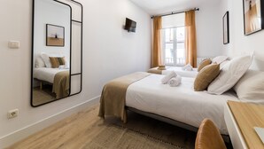 A bedroom with a bed, a mirror, a TV, and a window with curtains. - GETARIA SUITE: superior apartment for 4 PAX. Pedestrian street. 2min walk from La Concha beach (San Sebastián)