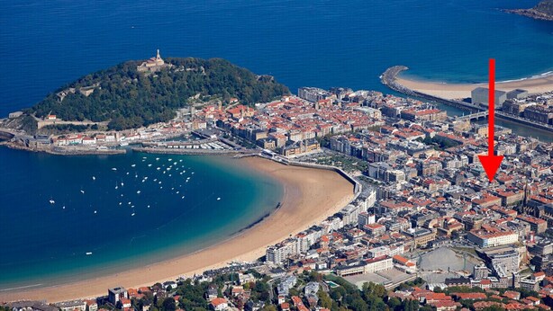 An aerial view of a coastal city with a prominent hill, a beach, and a dense urban area. - GETARIA SUITE: superior apartment for 4 PAX. Pedestrian street. 2min walk from La Concha beach (San Sebastián)