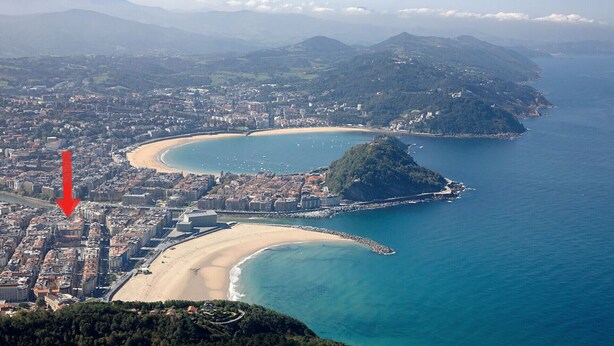 An aerial view of a coastal city with a prominent beach, a peninsula, and a dense urban area. - ZABALETA SUITE: 6 PAX Superior apartment. Practical and distinguished. 500 meters from the beach (San Sebastián)