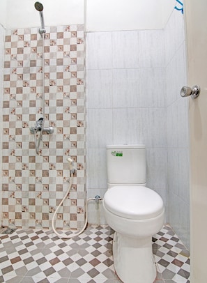 A bathroom with a checkered floor, a toilet, and a shower with a hose.