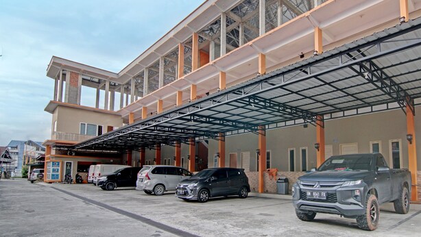 A multi-story parking structure with a covered walkway and several vehicles parked underneath. - OYO 91949 Ameera Homestay Syariah (Pekanbaru)