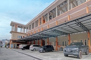 A multi-story parking structure with a covered walkway and several vehicles parked underneath.