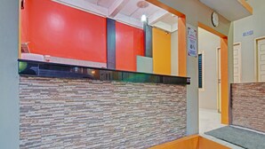 A reception area with a check-in counter, a clock, and a sign indicating a 10% discount. - OYO 91949 Ameera Homestay Syariah (Pekanbaru)