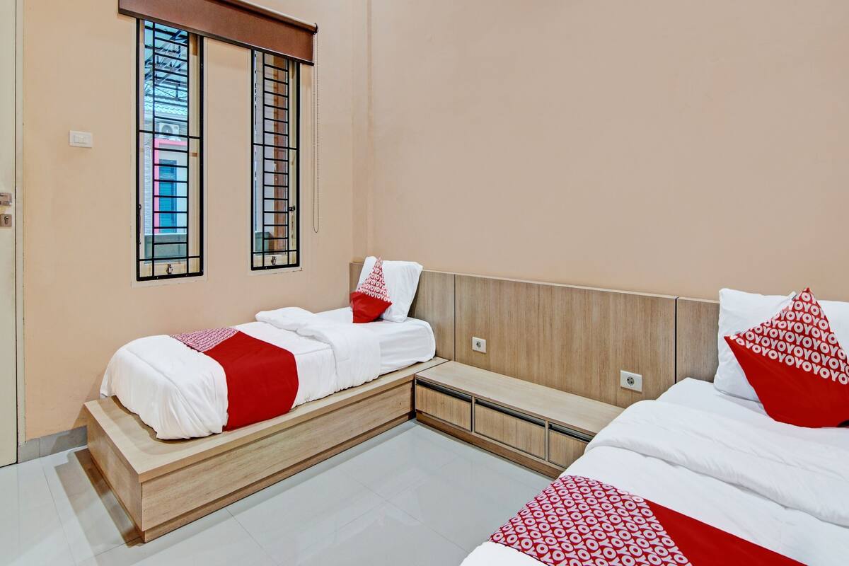 Ein Hotelzimmer mit zwei Betten, einer Holzbank und einem Fenster mit Gitterstäben.