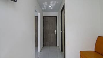 A hallway with a closed door at the end, a small table, and a sofa.