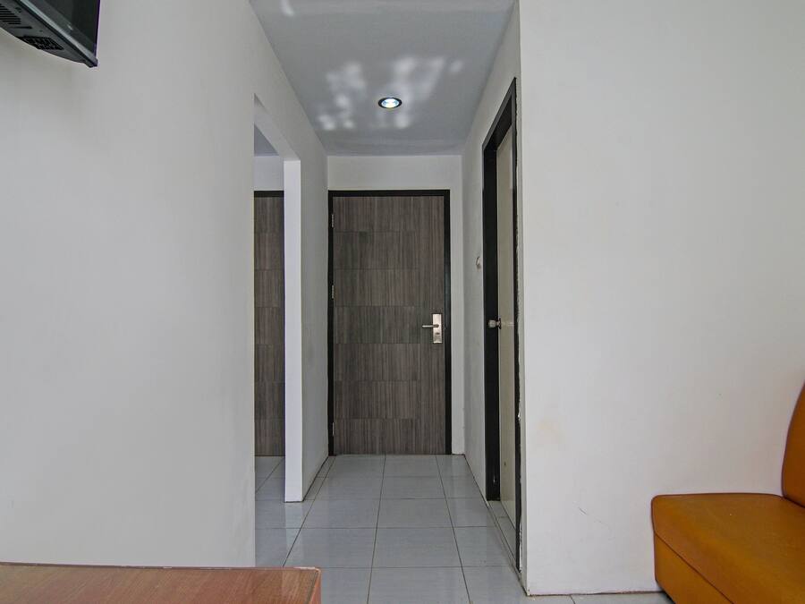 A hallway with a closed door at the end, a small table, and a sofa.