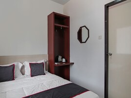 A hotel room with a bed, a wardrobe, a mirror, and a door.
