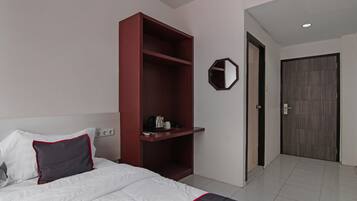 A hotel room with a bed, a wardrobe, a mirror, and a door.