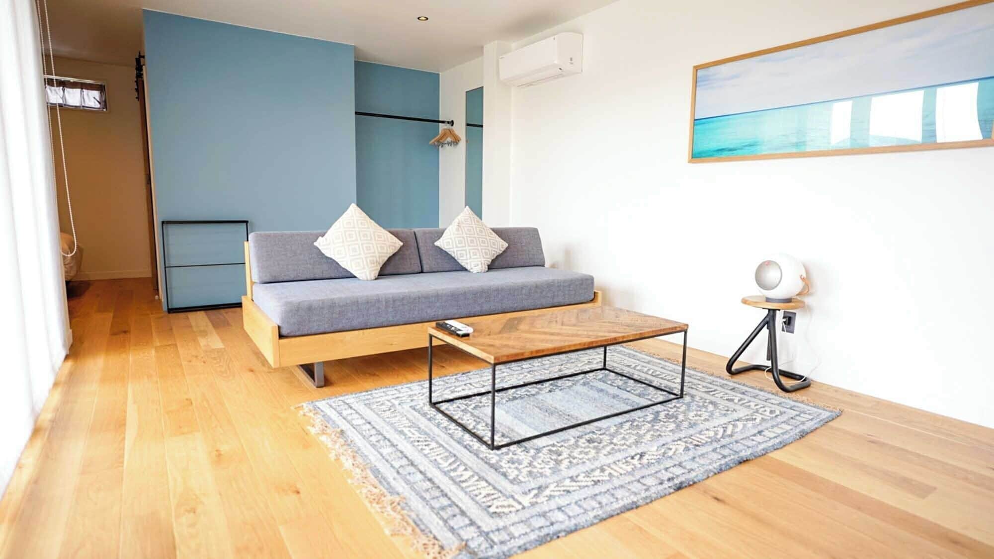 A modern living room with a sofa, a coffee table, a rug, and a painting on the wall.