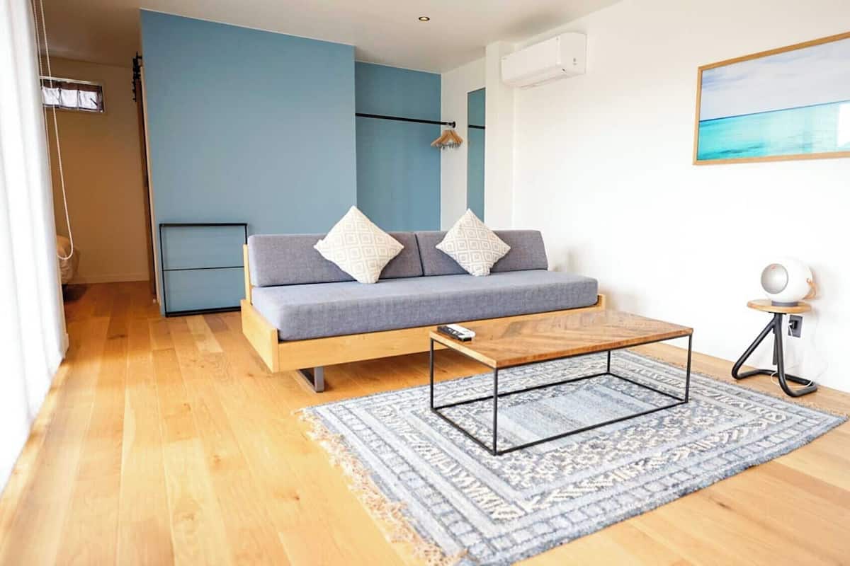 A modern living room with a sofa, a coffee table, a rug, and a painting on the wall.