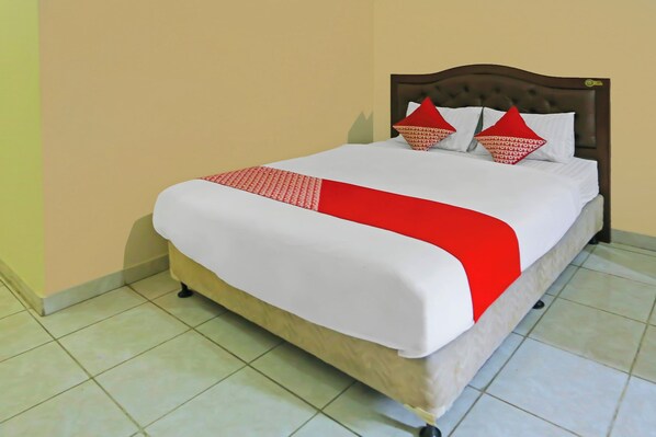 A neatly made bed with a white and red bedspread, a wooden headboard, and two red pillows.
