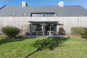 A modern house with a covered patio, a wooden fence, and a well-maintained lawn.