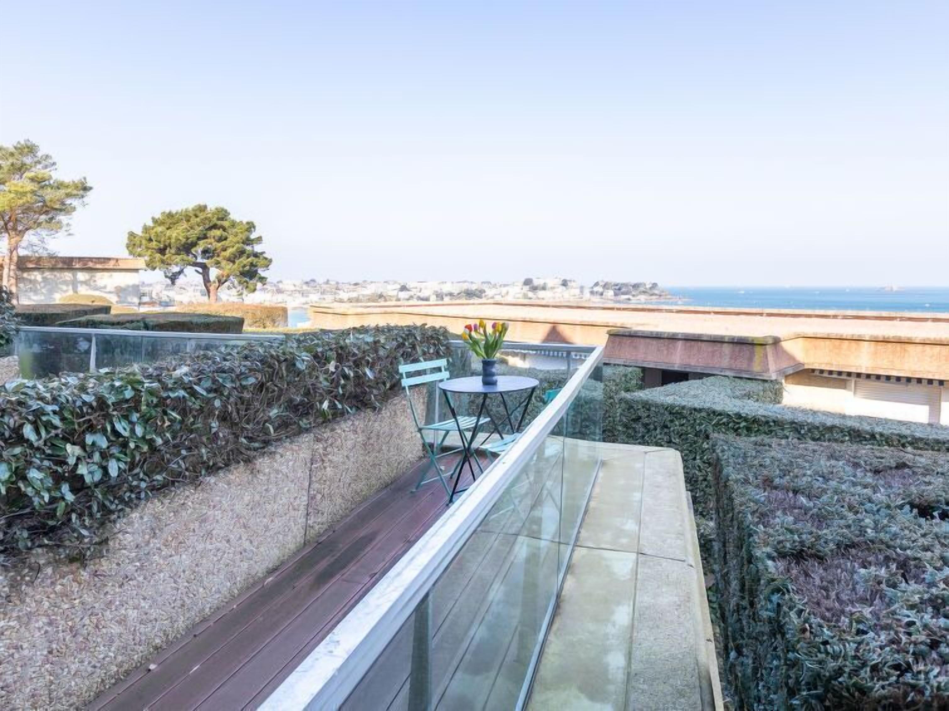 A rooftop terrace with a table and chairs, overlooking a coastal cityscape.