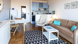 A compact living space with a kitchenette, a dining area, and a seating area with a sofa and a coffee table. - Le Parc de La Ronceray by Interhome (Dinard)