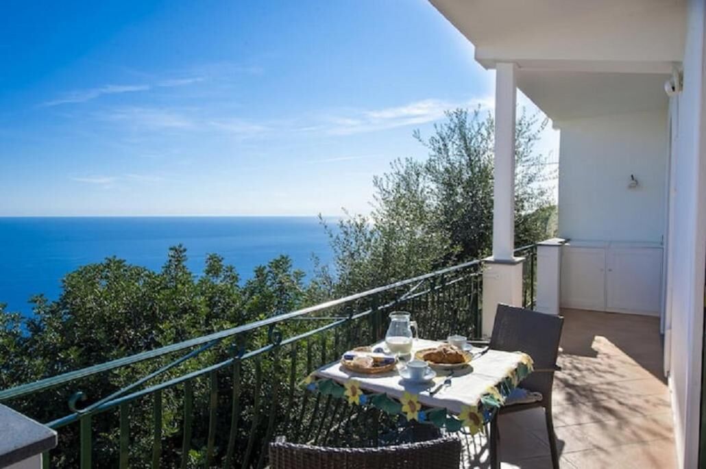 A balcony with a table set for breakfast overlooking the sea.