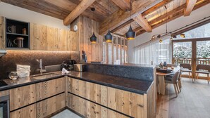 A modern kitchen with wooden cabinetry, a marble countertop, and pendant lighting.