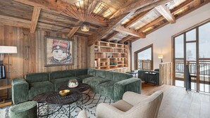 A cozy living room with a sectional sofa, a coffee table, and a bookshelf.