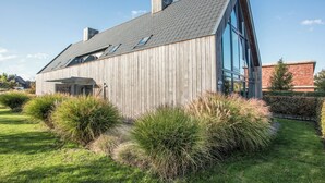 Una moderna casa in legno con tetto spiovente, ampie finestre e un giardino curato.