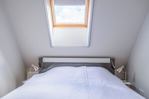 Une chambre à coucher avec un puits de lumière, un lit, des lampes de chevet et une table de chevet.