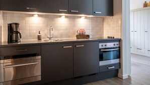 Una cucina moderna con mobili scuri, forno a incasso, macchina del caffè e lavello.