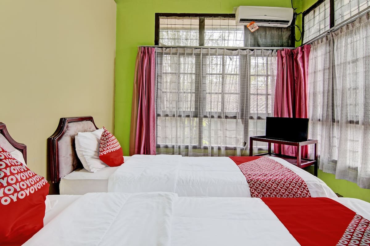A hotel room with two beds, a TV, and a window with curtains.
