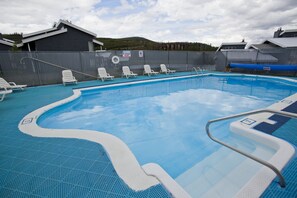 Ein Pool mit weißen Liegestühlen und einer Umzäunung.