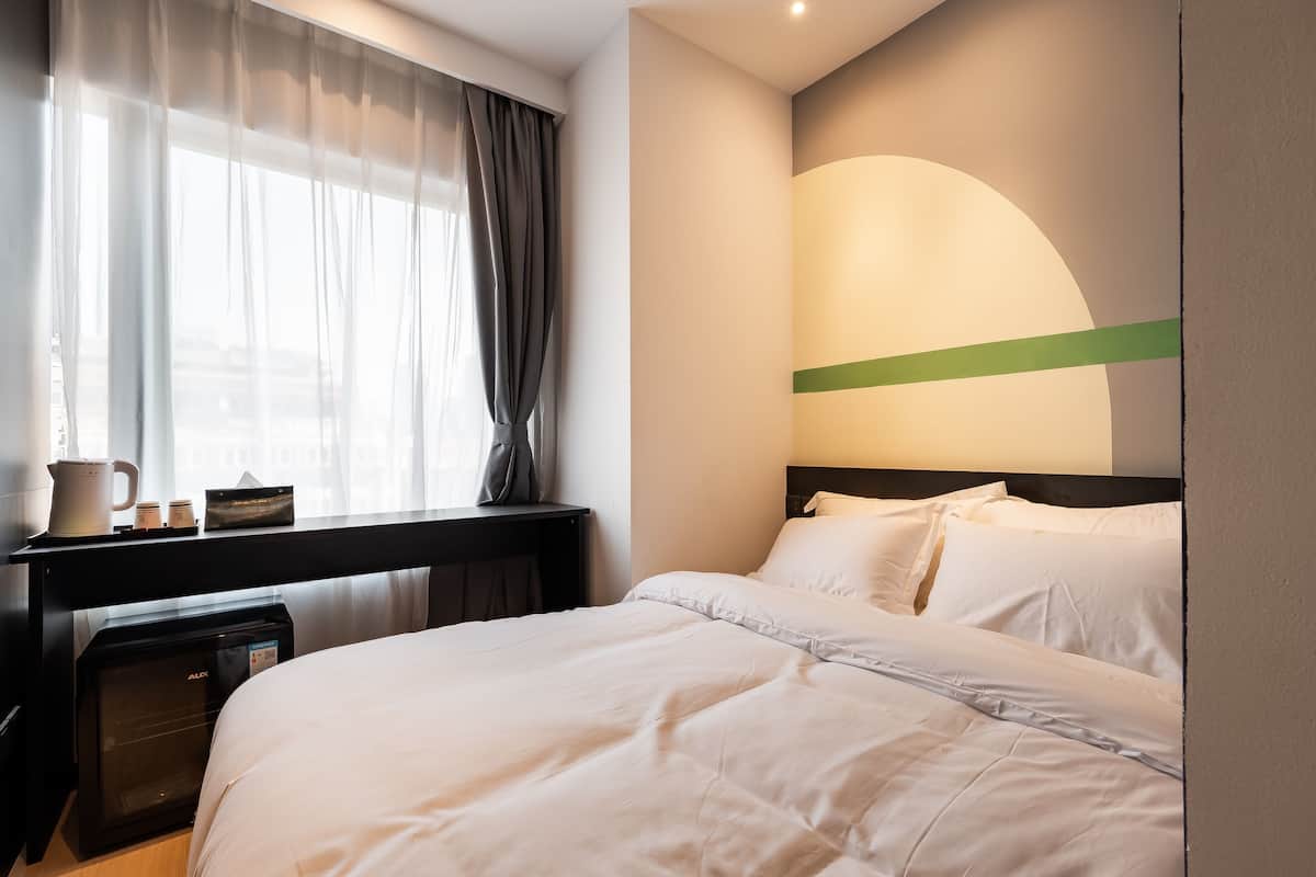 Une chambre d’hôtel avec un lit, un bureau doté d’une machine à café et une lampe fixée au mur.
