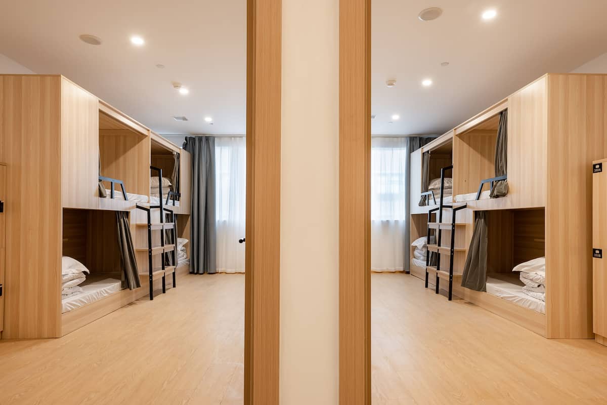 Une pièce aux murs recouverts de miroirs, avec des lits superposés, des murs en bois et un plancher de couleur claire.