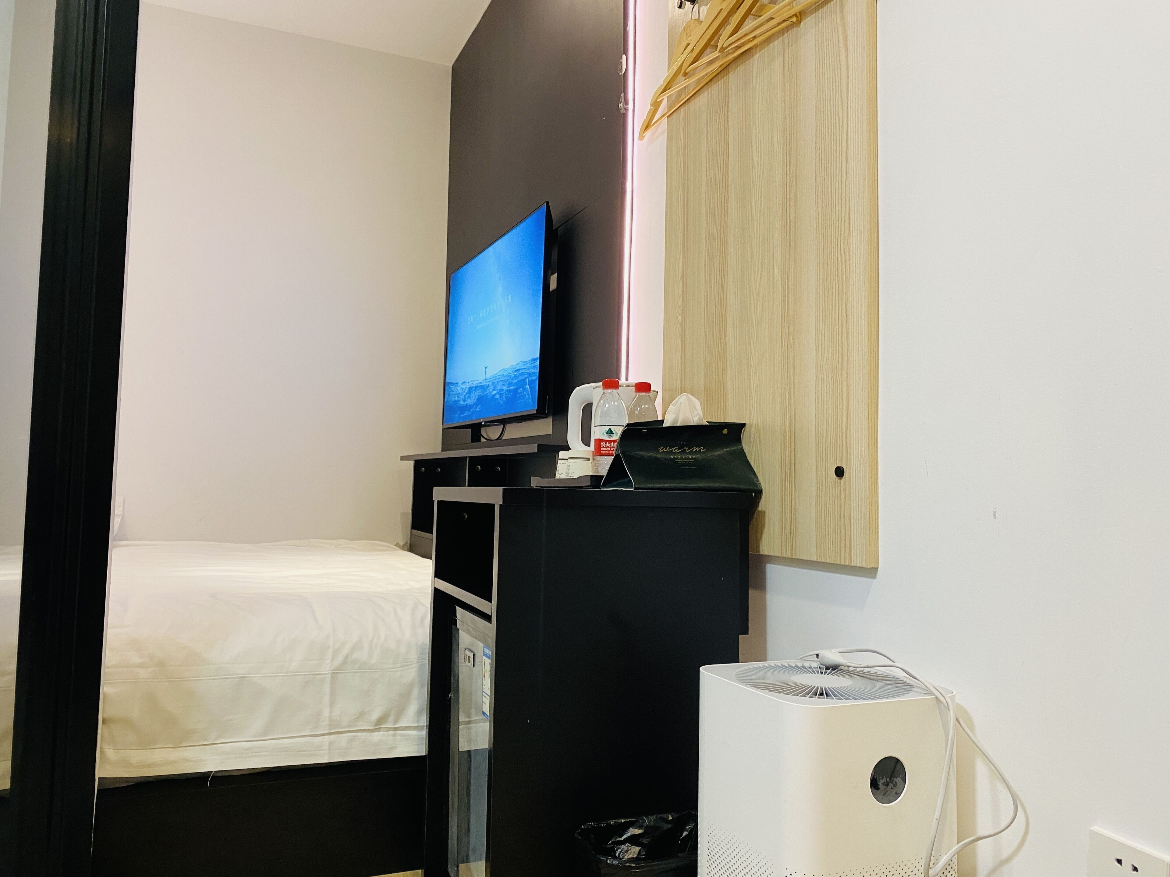 Ein Hotelzimmer mit einem Bett, einem Fernseher, einem kleinen Schreibtisch mit Computer und einer Heizung.