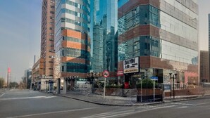 En modern byggnad med en böjd glasfasad, som ligger intill en lägre byggnad med en fasad av tegel.