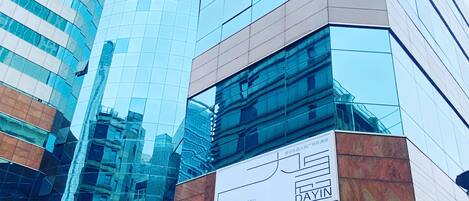A modern hotel with a glass facade, a visible sign indicating it is a hotel, and a traditional building with Chinese characters in the foreground.
