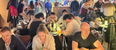 A busy restaurant with multiple tables and patrons.