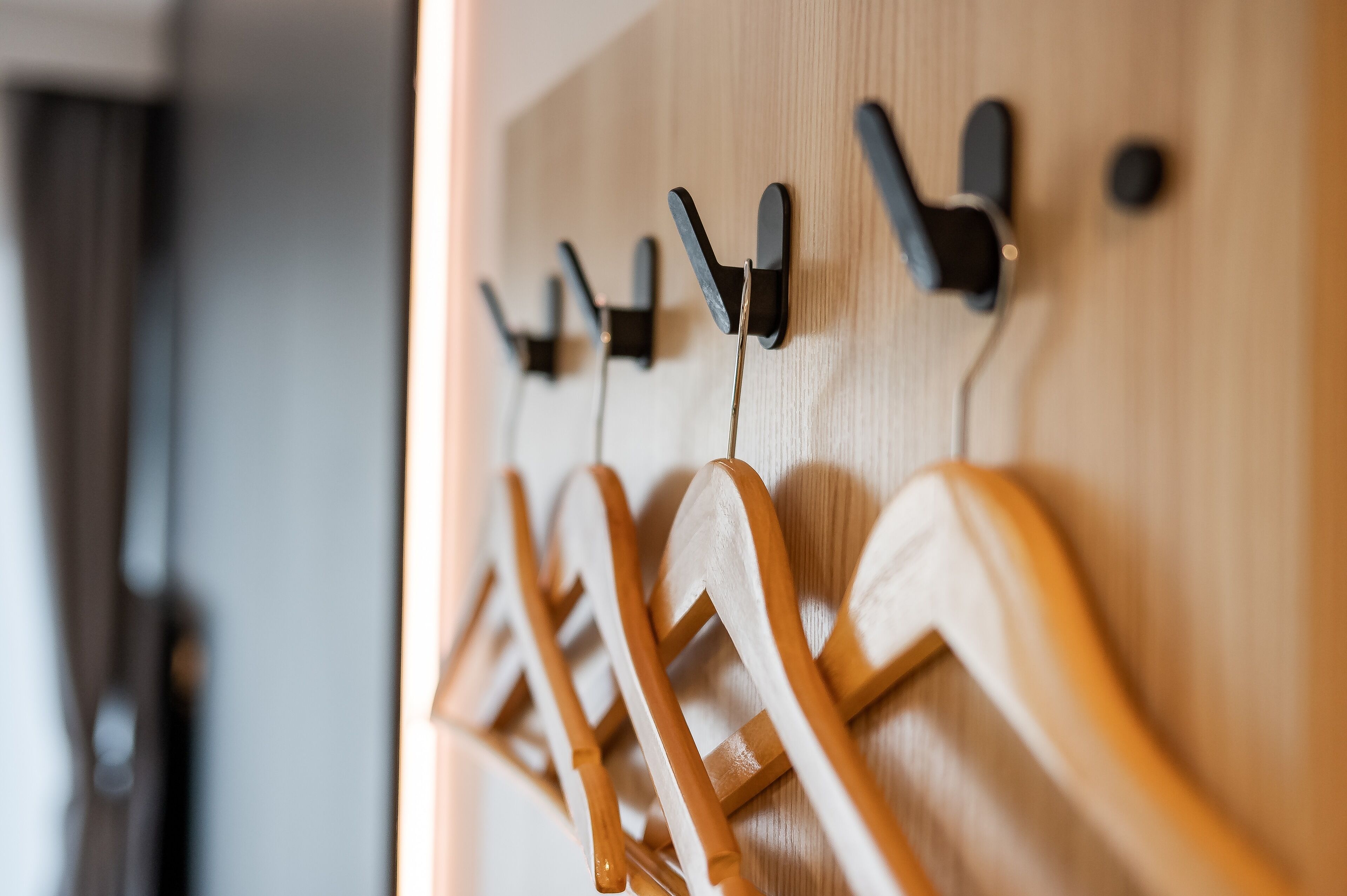 A wooden wall with multiple hooks and a coat rack.