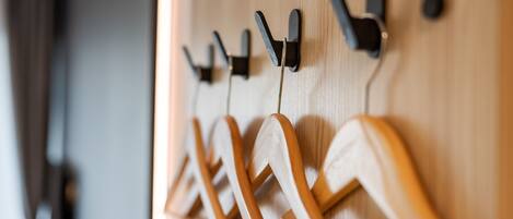 A wooden wall with multiple hooks and a coat rack.