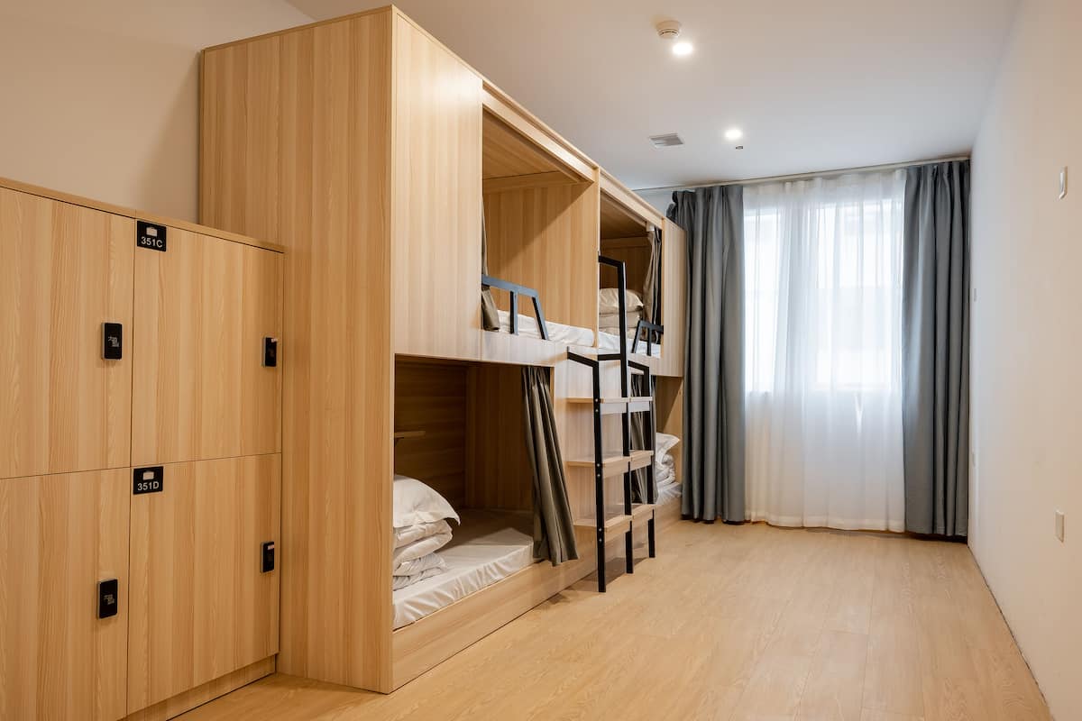 Une chambre avec des lits superposés, une armoire et une fenêtre avec des rideaux.