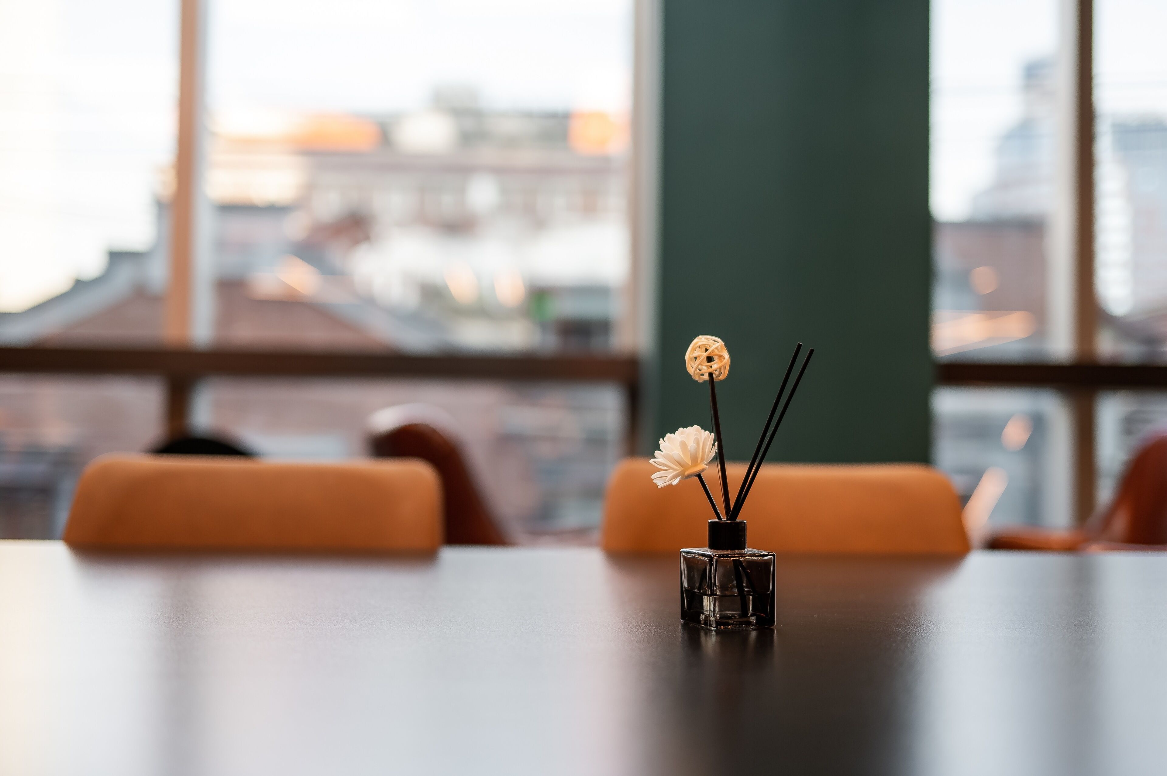 A table with a small black vase containing a white flower and two black sticks.