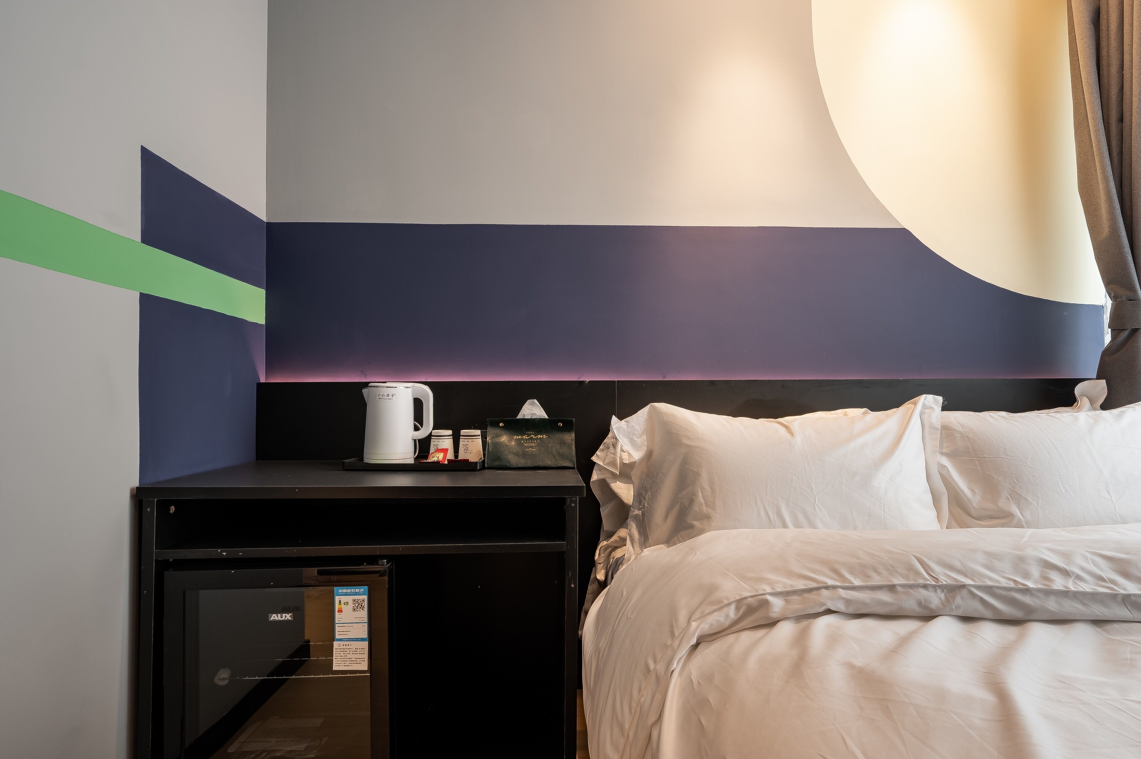 Habitación de hotel con cama, una mesita con cafetera, pañuelos desechables y minibar.