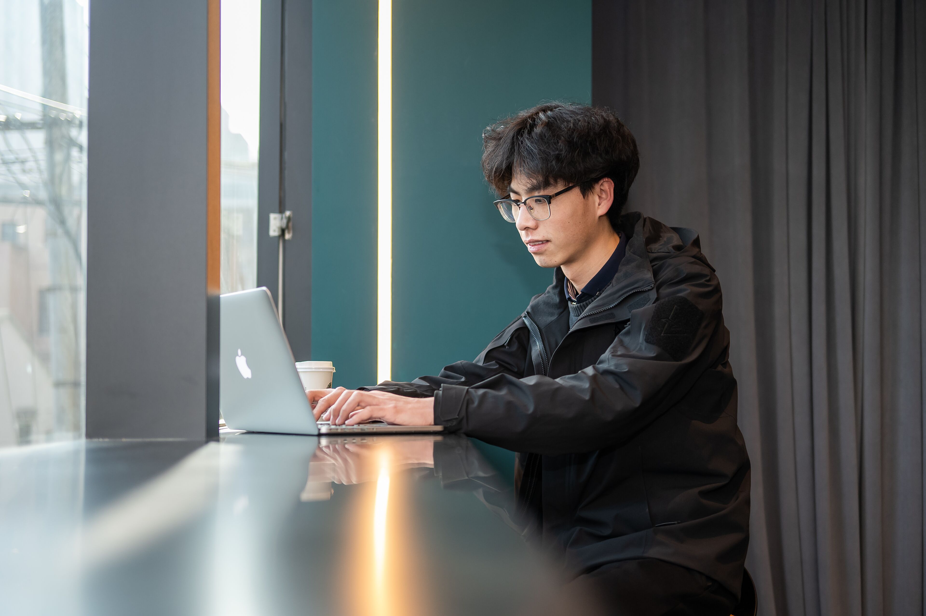 A person sitting at a table with a laptop and a coffee cup.