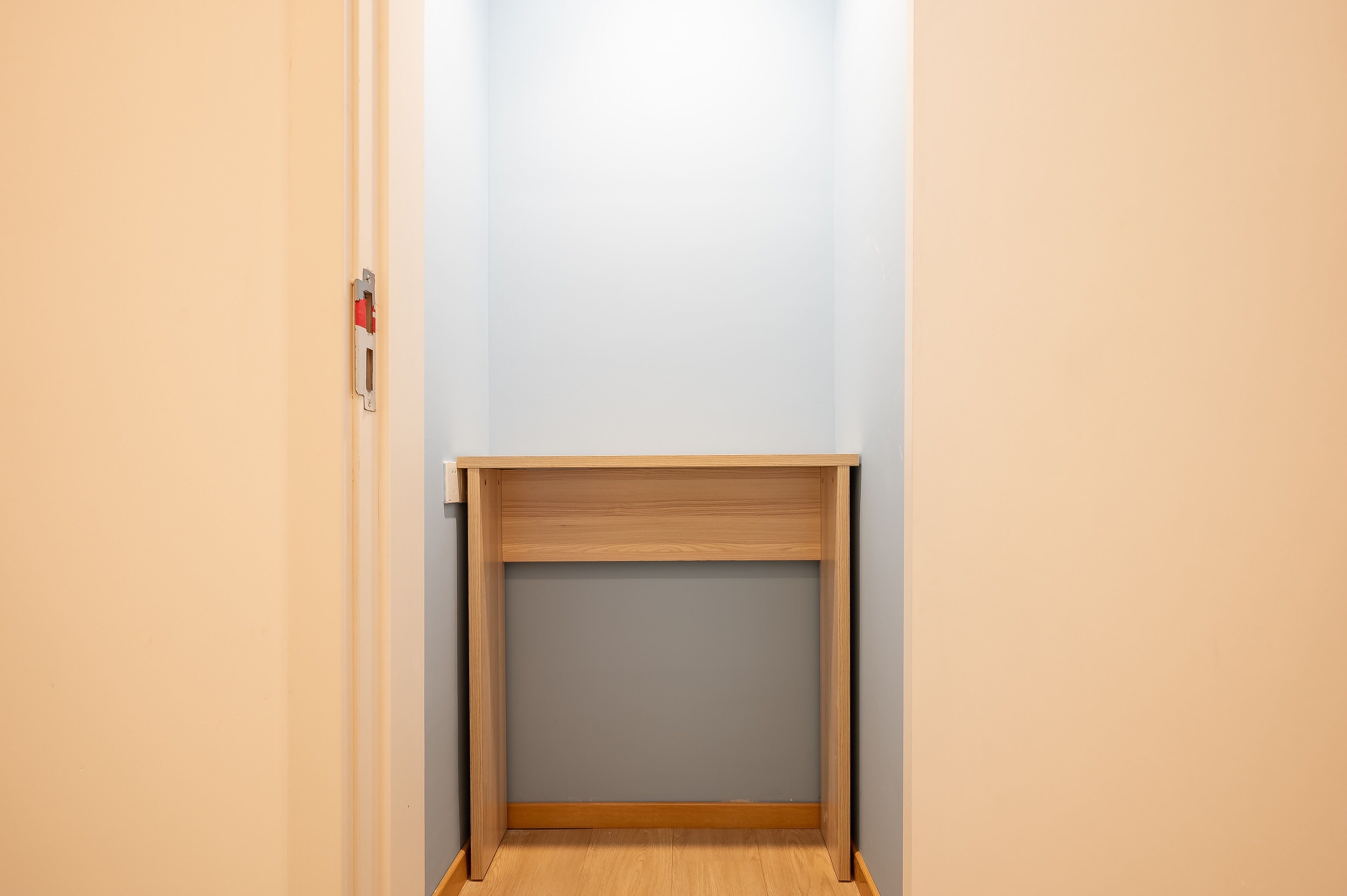 Een kleine, afgesloten ruimte met een houten tafel en een deur.