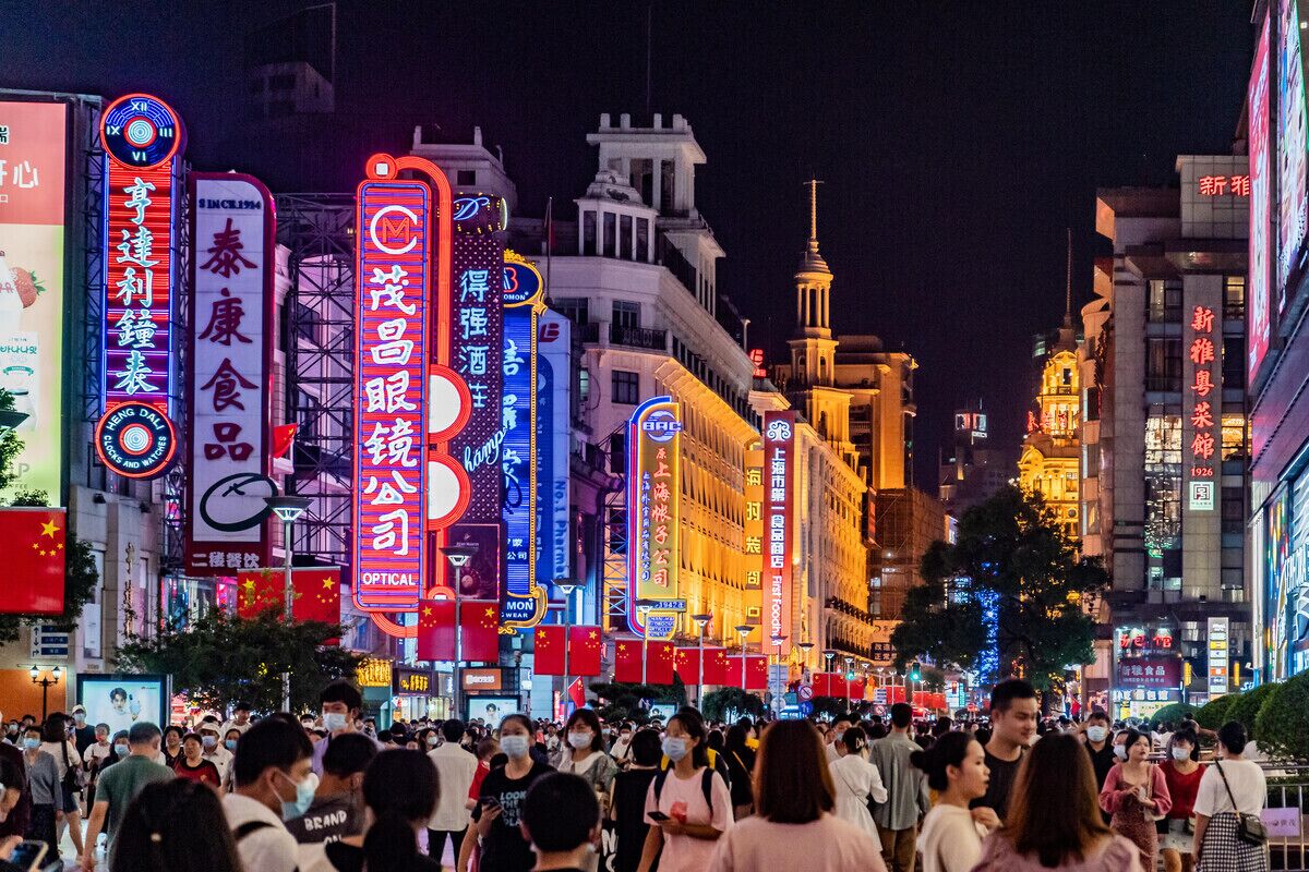 A busy urban street at night with illuminated signs and buildings.