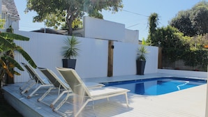 A swimming pool with a wooden deck and lounge chairs.