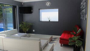 A modern living room with a large window, a red sofa, and a white couch.