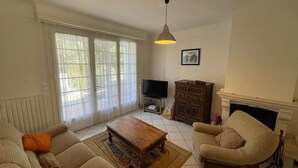 A living room with a sofa set, a wooden coffee table, a television, and a fireplace.
