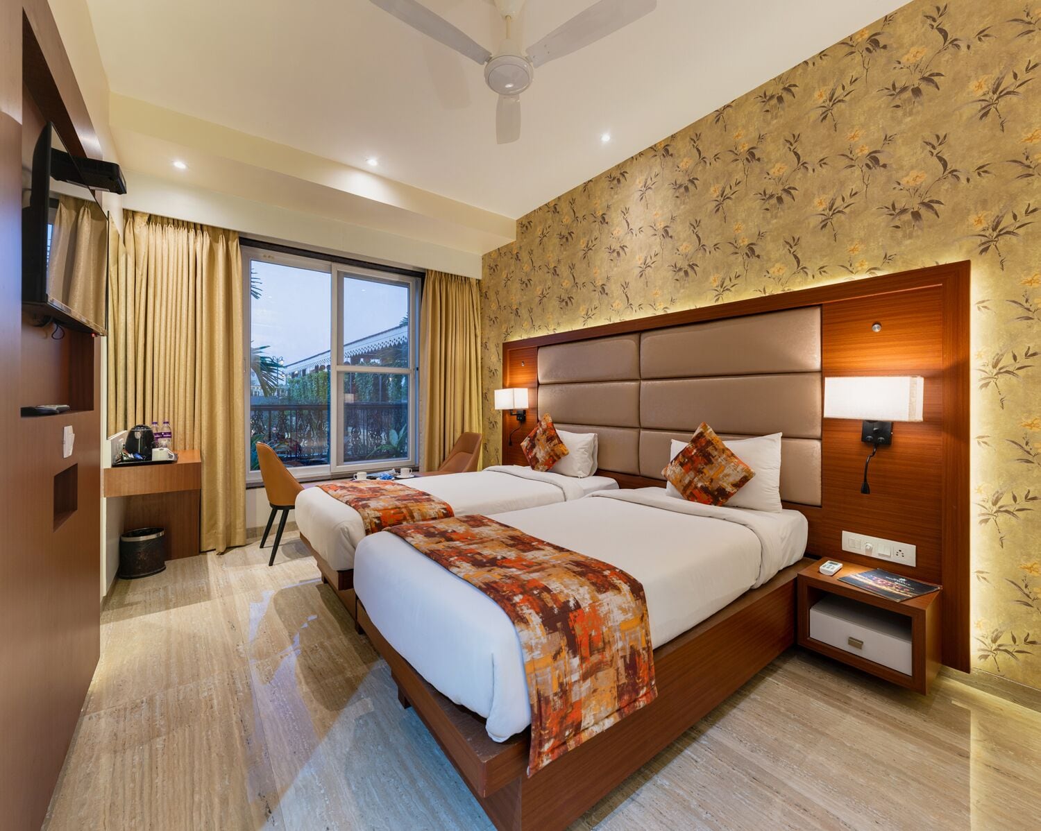 Une chambre d’hôtel avec deux lits, un bureau, une chaise, une télévision et une grande fenêtre donnant sur un beau paysage.