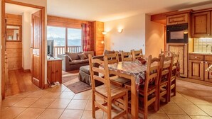 A cozy cabin interior with a dining area, wooden furniture, and a kitchen. - Ski-in/ski-out apartment, 4 bedrooms, 8 ppl, covered parking, WiFi (Les Arcs 1800)